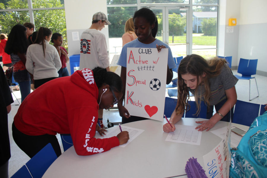 Junior Madison Grady helps two students sign up for Active with Special Kids (ASK) club.