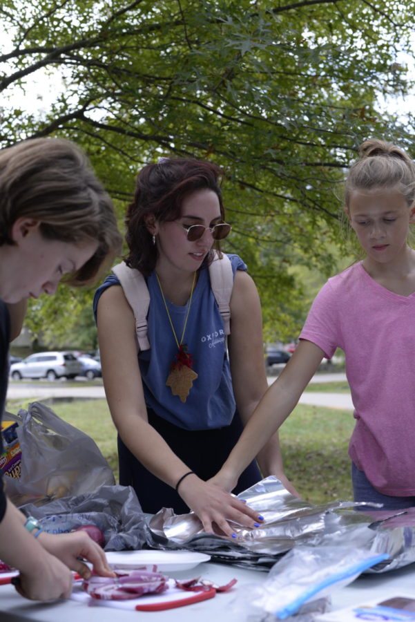 Senior Annie McNutt assists the campers in preparation for their cooking class. In outdoor cooking, students enjoyed tacos and other dishes.