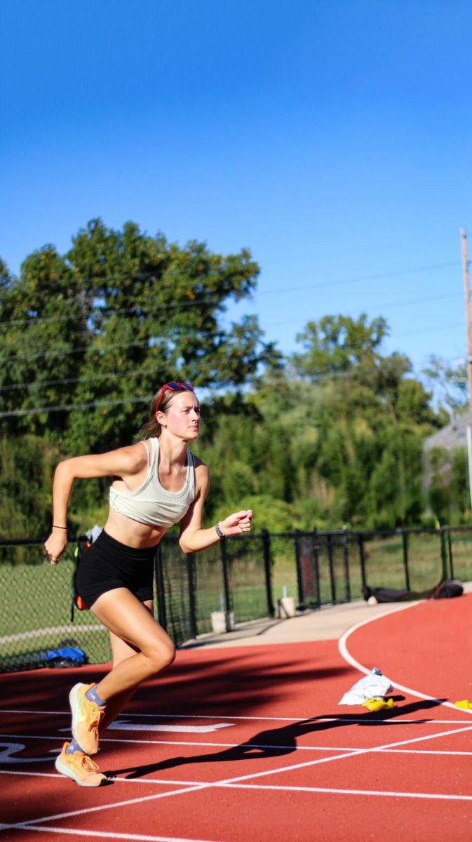 Brinker takes a lap around the track to warm up for her workout. She had just begun working out with her team after a short break preceding the off-season. “I just started working out two weeks ago, but when I was on my break, I realized how much I missed running,” Delaney said. “Like, wow, that was such a big part of me.” (Photo illustration by Mac Huffman and Vincent Hsiao)