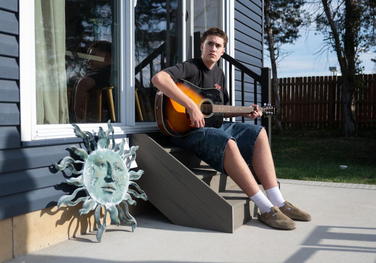 ABOVE: Duncan Kitchen (10) plucks the strings of his guitar at his home. Duncan’s  older brother inspired him to start playing the guitar two years ago. “On any given day [in Alaska], you could walk up the mountain start a campfire [and] play guitar,” Duncan said. (Photos by Vincent Hsiao)