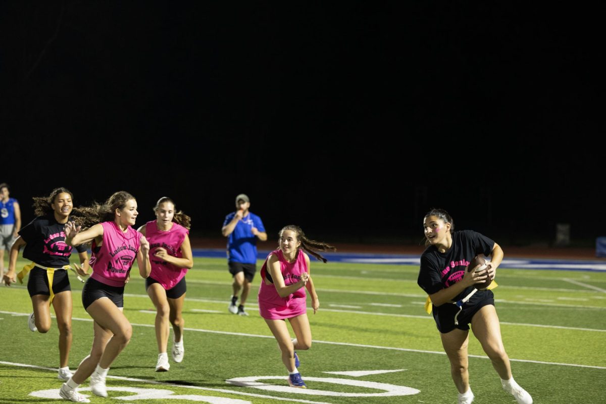 Juniors and seniors compete at the annual Powderpuff football game Sept. 29. Campbell Cross (12) cheered on the sidelines with the boys cheer team, The Squad. “Powderpuff was really fun this year, especially getting to cheer on the sidelines with the boys and rushing the field after the senior win,” Cross said.