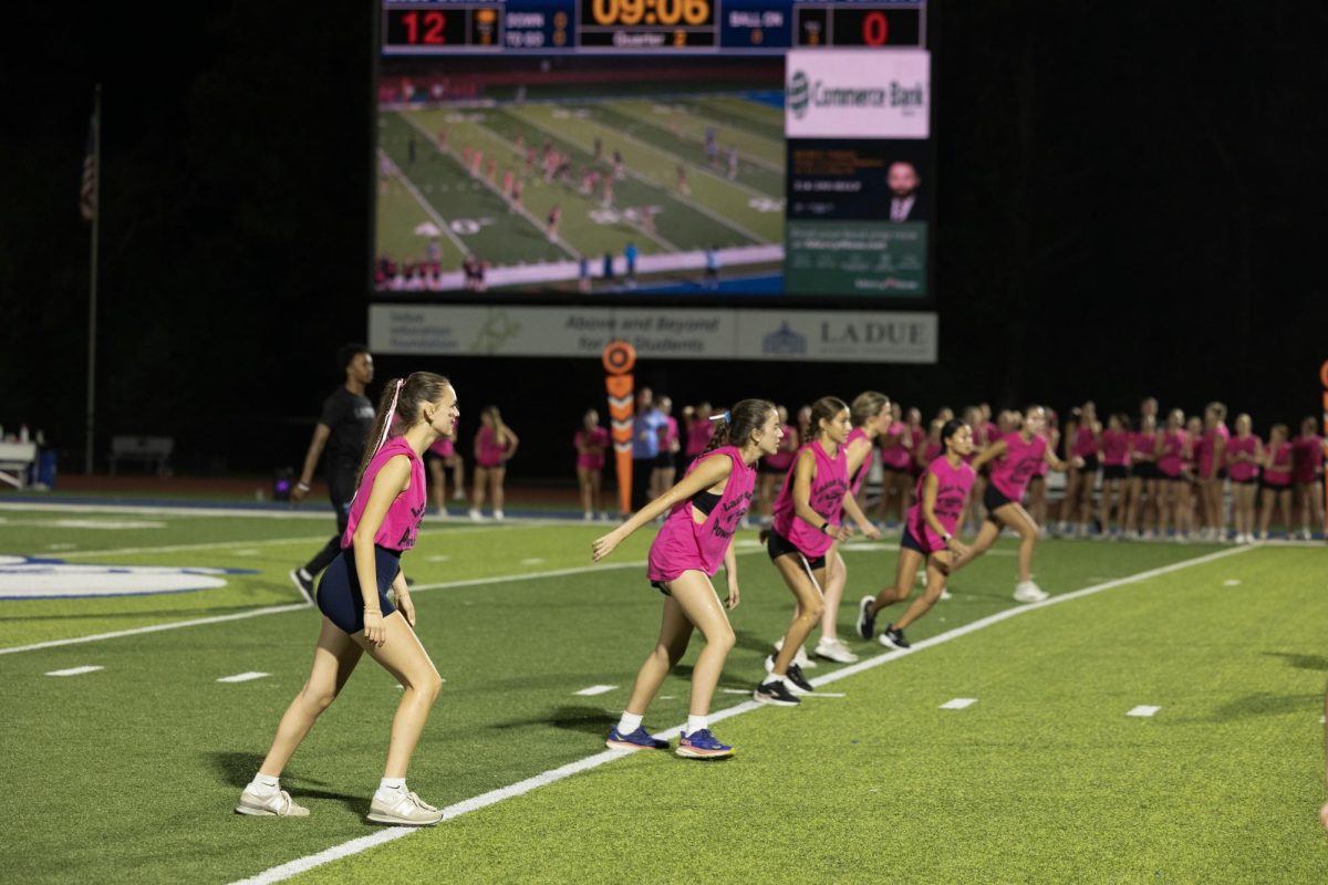 Juniors and seniors compete at the annual Powderpuff football game Sept. 29. Campbell Cross (12) cheered on the sidelines with the boys cheer team, The Squad. “Powderpuff was really fun this year, especially getting to cheer on the sidelines with the boys and rushing the field after the senior win,” Cross said.