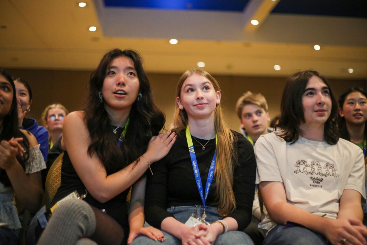 Senior Celina Zhou places her hand on the shoulder of senior Fiona Van Allen as they watch the names appear from fifth to first for the Artist of the Year competition. Van Allen was up for the award and would go on to win the competition. 