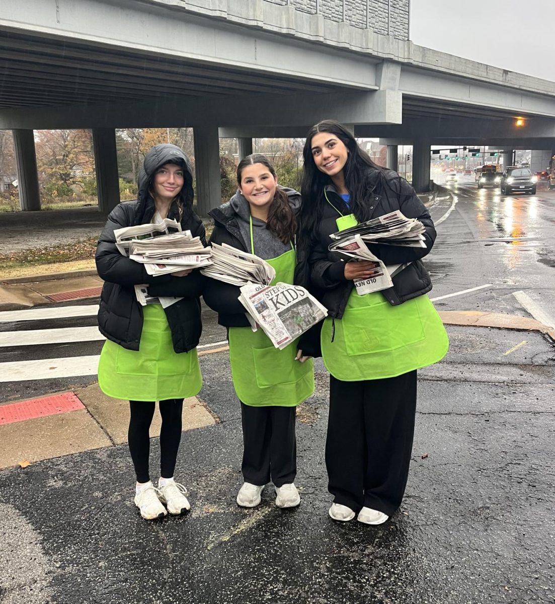 Annie Tilghman (11), Alex Press (11) and Gigi Stoeva (11) hold their newspapers. Stoeva has already completed her required service hours for this semester. “I really enjoyed doing Old Newsboys because I felt like I was helping my community while being able to have fun with friends,” Stoeva said. 