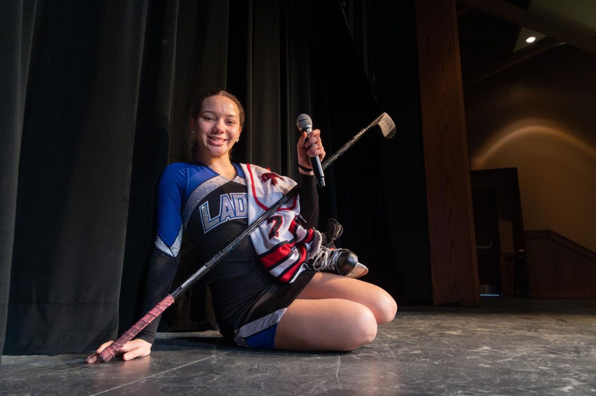 Microphone in hand and hockey jersey slung over a shoulder, Amara Loynd (9) poses for a portrait highlighting her extracurricular involvements. Outside of school, Loynd spends her time dancing for the Laduettes, playing club hockey, and performing at the Muny.