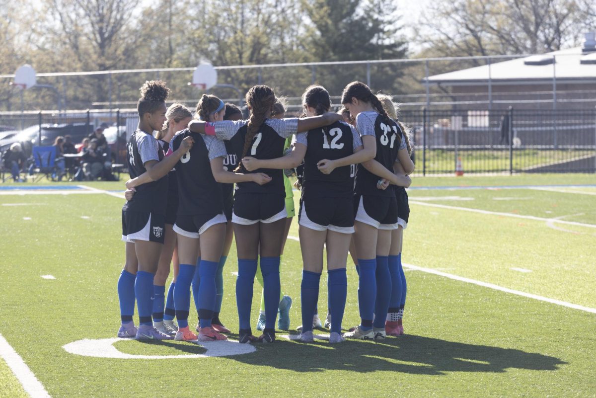 The girls soccer team huddles together in a game against Webster April 15, 2025. They won the game 2-1. “I am looking forward to being able to be a leader this year, now that I’m an upperclassman,” player Charlotte Wilson (11) said. “[I am also excited for] everyone to have a great experience with this season.”