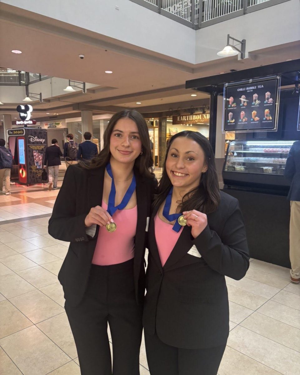 Alia Al Husseini (12) and her partner Joie Sandler (12) smile with their first place medals. They have been members of DECA for four years. "It was a fun experience," Husseini said.