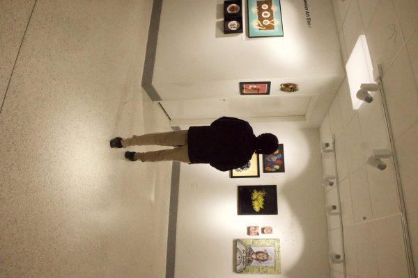 Trirease Edwards (11) observes art pieces in Spirtas Art Gallery on April 15. The gallery displayed seniors' artwork from the year. "The gallery shows the creativity throughout the school," Edwards said. "The masked painting is my favorite. It has a lot of detail and it shows the artists hard work."