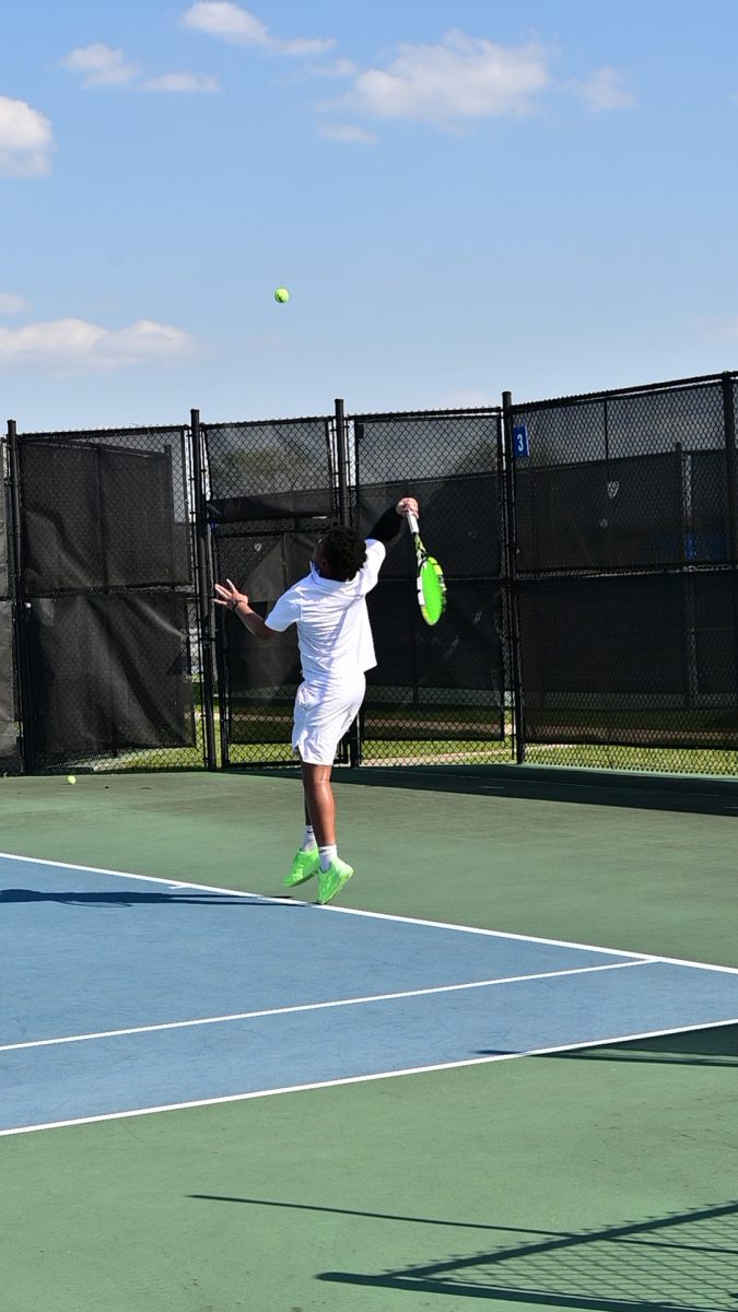 Jumping up to hit a serve, Ugoji Egbujo (11) swings up on the ball. Egbujo has been playing tennis for eight years. "I enjoy playing tennis because it's relaxing," Egbujo said. "It allows me to express myself and experience thing on my own on the court." (photo by k. chan) 